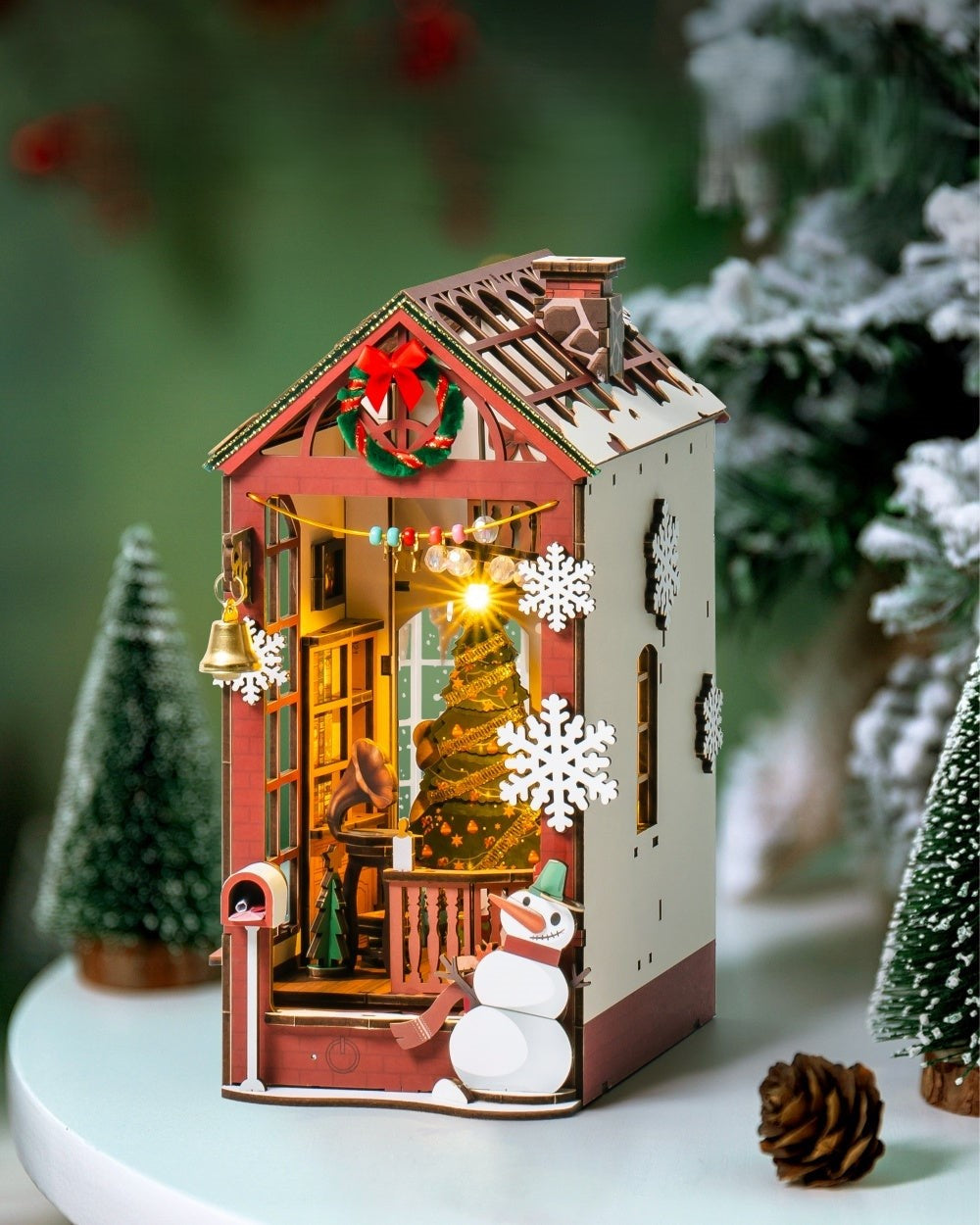 Decorative Christmas house with lights, snowman, and trees on a blurred background
