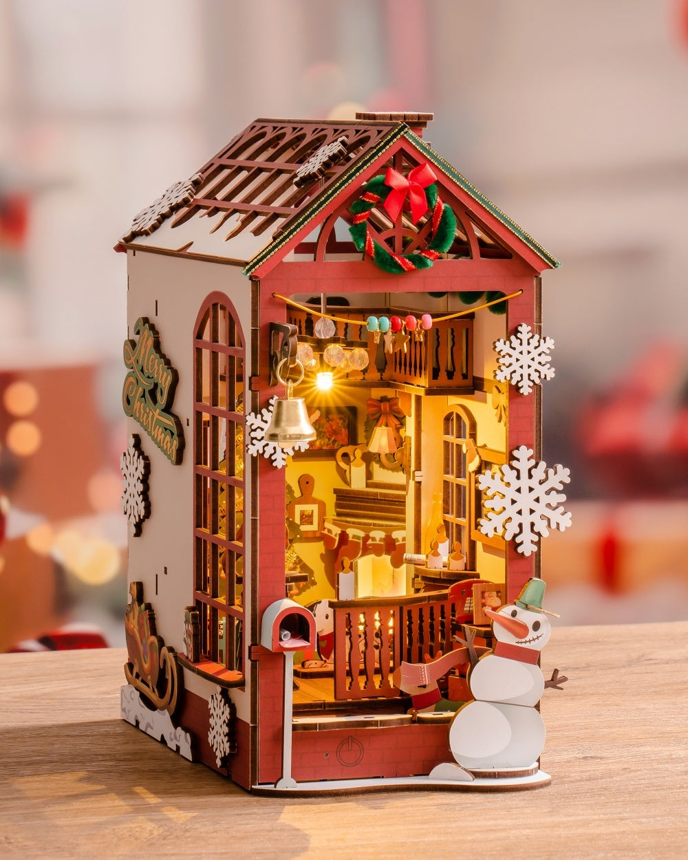 Decorative wooden house with lights and snowman on a blurred background