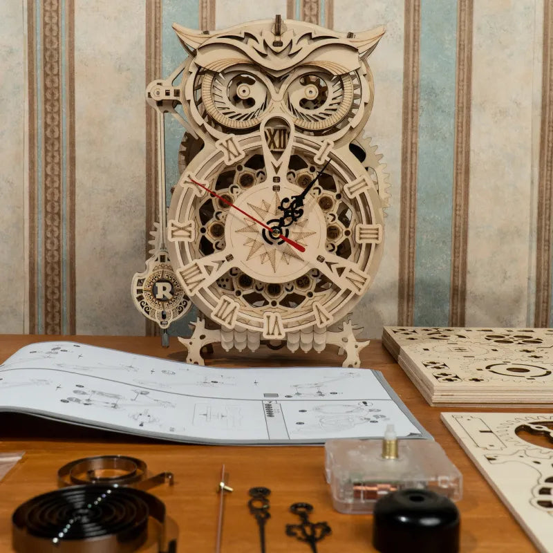 Wooden owl clock with mechanical design on a table with tools and instructions.