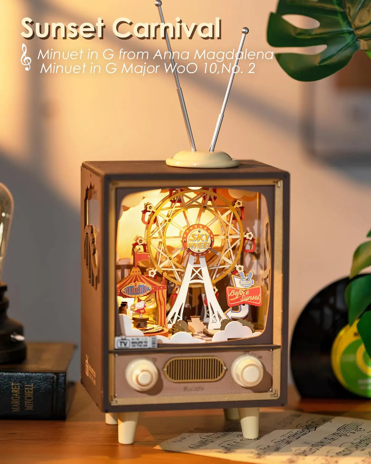 Vintage-style music box with a Ferris wheel design, resembling an old television set, on a wooden surface.
