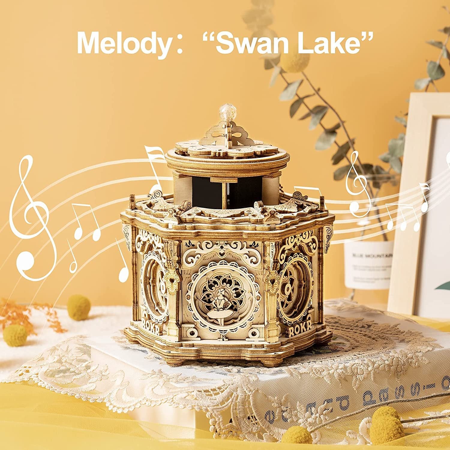 Decorative music box playing 'Swan Lake' with decorative elements on a yellow background